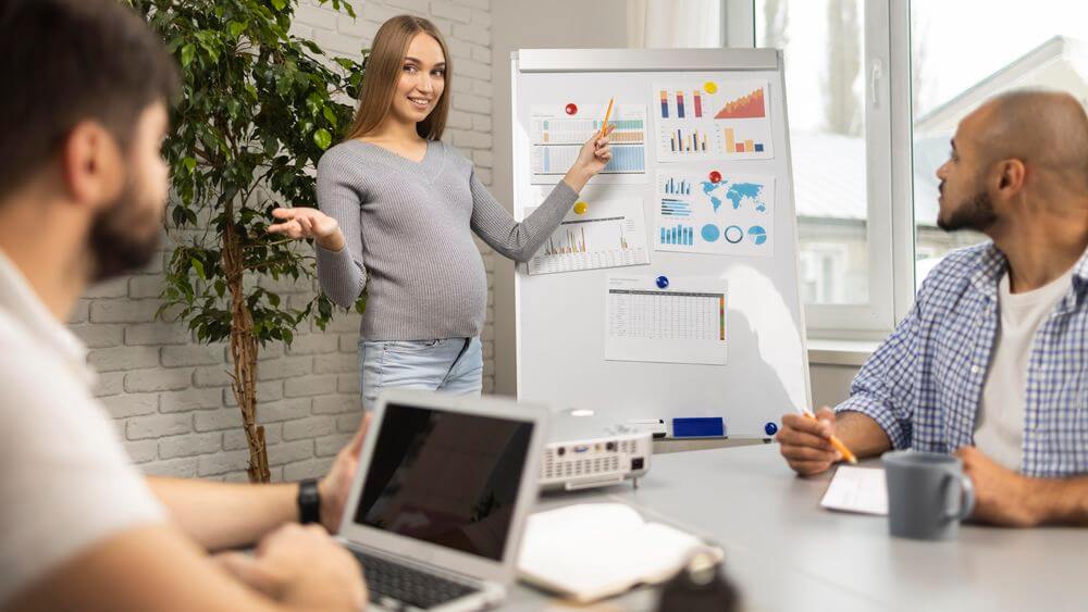 Pregnant businesswoman giving presentation, women's health in the workplace