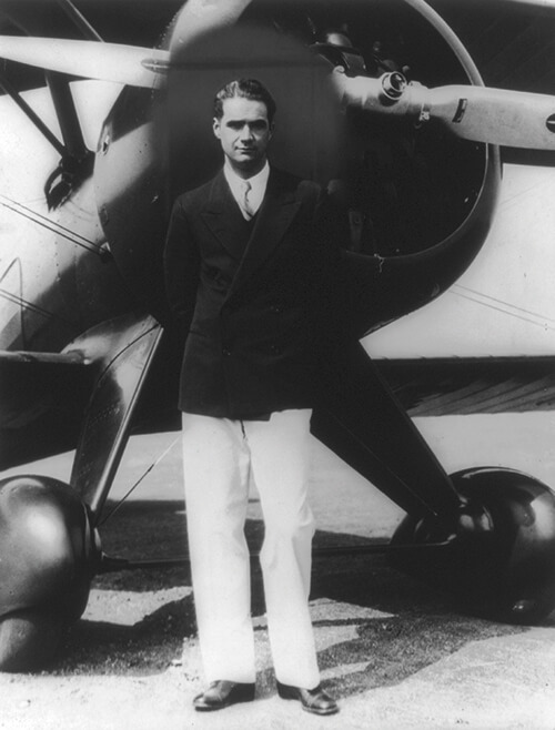 Howard Hughes, standing in front of a plane