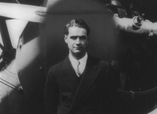 Howard Hughes, standing in front of a plane