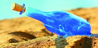 Blue glass bottle on sand