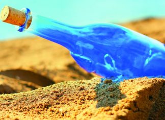 Blue glass bottle on sand