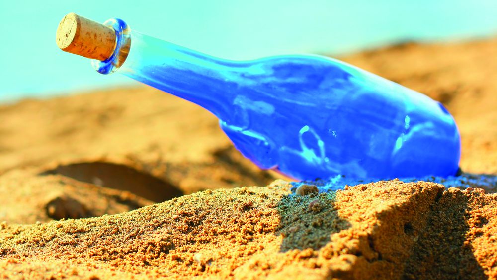 Blue glass bottle on sand